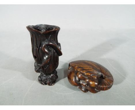 A vintage dark wood Netsuke depicting a small frog type animal carrying a large tree trunk on its back with another smaller f