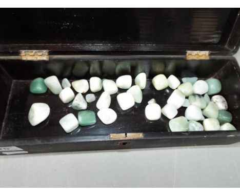 A 19th century black lacquered box containing 38 jade stones.
