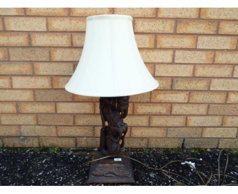 An Oriental, highly carved wooden lamp depicting a dragon, with shade.