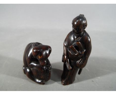 A vintage Japanese dark wood Netsuke depicting a Samurai, signed and a vintage Japanese Netsuke depicting a dog carrying a la