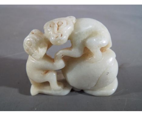 A Chinese white jade or hardstone carving depicting two monkeys and a peach, leaf design to base, approximately 7 cm (l)