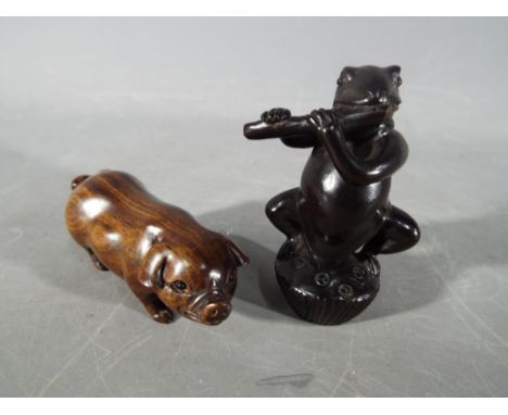 A vintage Japanese dark wood Netsuke depicting a frog type creature possibly playing aflute, signed and a vintage dark wood N