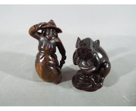 A vintage Japanese dark wood Netsuke depicting a large mouse or rat carrying its catch, signed and a vintage Japanese dark wo