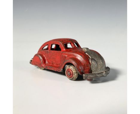 A vintage toy car modeled after the iconic 1930s Chrysler Airflow, featuring a vibrant red hue with detailed molded lines and