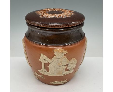 Stoneware jar with raised relief hunting scenes. Jar has brown glazed banding with matching lid decorated with raised leaf de