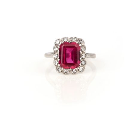 A synthetic ruby and diamond ring, early 20th century, claw-set with a step-cut synthetic ruby, within a scalloped border of 