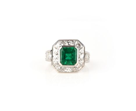 An emerald and diamond cluster ring, the square emerald-cut emerald set within a border of French-cut diamonds with further g