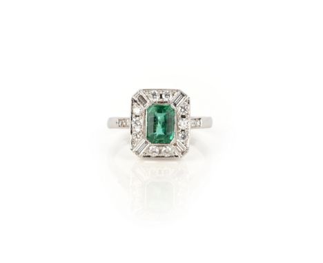 An emerald and diamond ring, collet-set with a step-cut emerald, within a geometric border of brilliant-cut and baguette diam