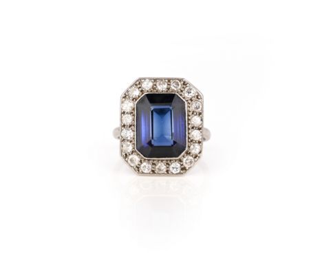 A synthetic sapphire and diamond ring, 1920s, set with a step-cut synthetic sapphire within a millegrained border of circular