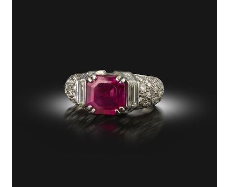 A ruby and diamond ring, claw-set with an octagonal step-cut ruby weighing 3.26 carats, to a geometric bombé mount set to the