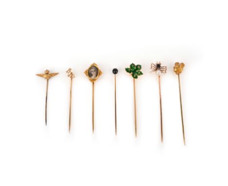 A collection of seven stick pins, early 20th century, comprising: one with a sycamore leaf in green enamel with the initials 