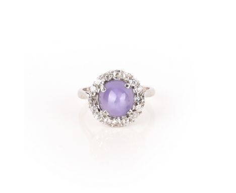 A star sapphire and diamond ring, claw-set with a cabochon violet star sapphire, within a border of circular-cut diamonds, mo