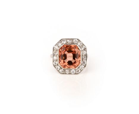 A topaz and diamond ring, early 20th century, set with a step-cut orange topaz within a millegrained border of circular-cut d