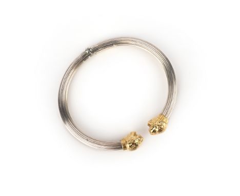 A silver bangle, Lalaounis, the hinged fluted silver bangle of torque design, each end terminating in a gilded lion's head, i