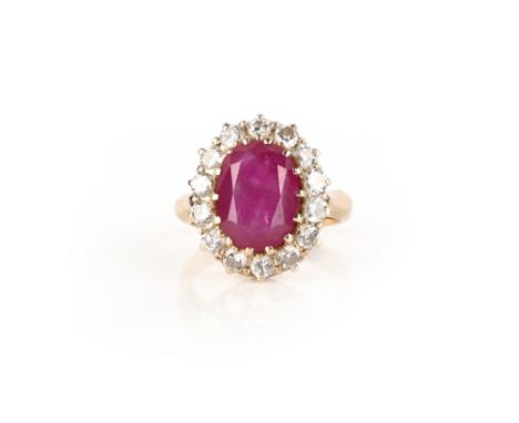A ruby and diamond cluster ring, the oval ruby set within a surround of round brilliant-cut diamonds in gold, size P