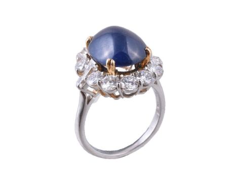 A French sapphire and diamond ring, the oval cabochon sapphire claw estimated to weigh 6.95 carats, within a surround of bril
