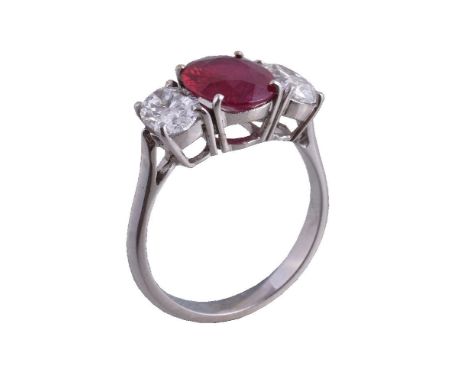 A ruby and diamond three stone ring, the central oval cut ruby estimated to weigh 2.42 carats claw set between two oval cut d