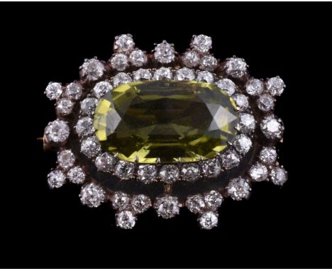 A Victorian peridot and diamond brooch, circa 1870, the oval cut peridot estimated to weigh 6.57 carats within a surround of 