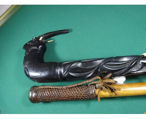 A malacca walking stick, 33½” with wood and leather handle; a heavily carved ebony walking stick with elephant design handle,