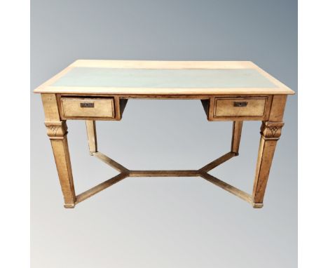 An early 20th century oak two drawer writing table with leather inset panel and understretcher 