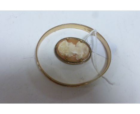 A 9ct gold bangle and a yellow metal mounted cameo.