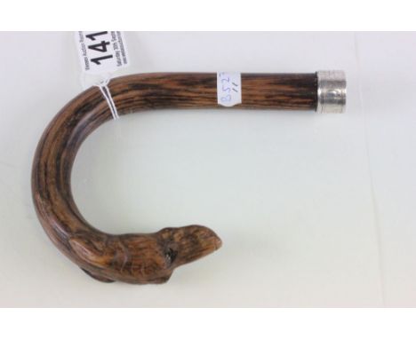 An antique walking stick handle in the form of a curved lurcher greyhound dog with glass eyes