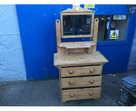 A stripped pine dressing table with mirror and shelf above and three draws below.
