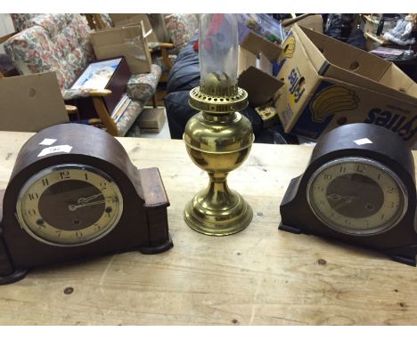 Two chiming mantle clocks and an oil lamp.