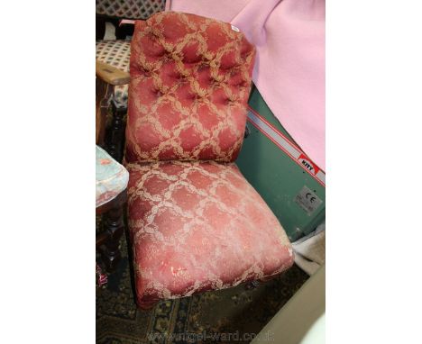 An elegant Victorian Nursing Chair, upholstered in red button-back foliage print fabric and standing on turned legs with cast