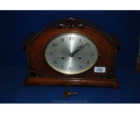 A wooden mantle clock having two crossed arrows on the oval shaped face