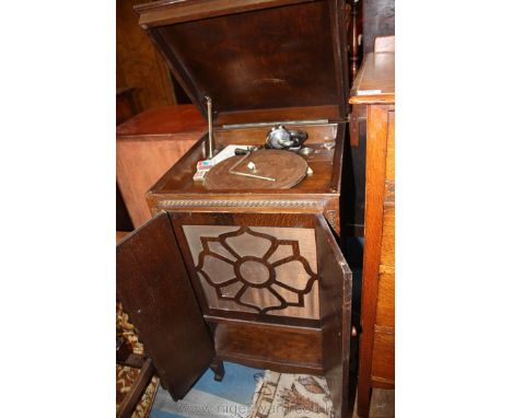 A 1930's Oak cabinet wind-up Gramophone, the moulded lifting lid opens to reveal a turntable with chrome style arm, over lowe