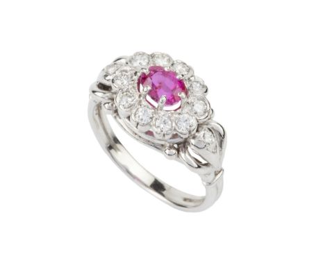 A ruby and diamond cluster ring, the oval cut ruby within a border of ten collet-set round brilliant cut diamonds, the shaped