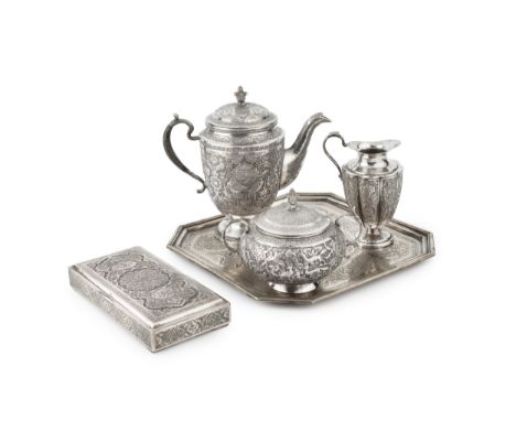 An Indo-Persian silver three piece tea service on tray, comprising teapot, sucrier and cover, and milk jug, intricately relie