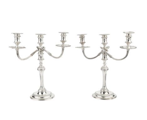 A pair of silver three light candelabra, the detachable branches with reeded arms and gadrooned drip trays, on fluted and sty