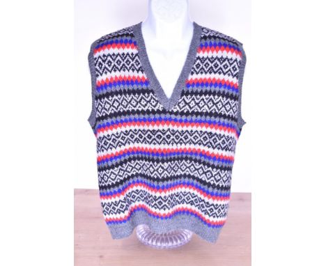 A vintage wool hand-knitted tank top / sweater vest, having a V neck and diamond pattern in grey, black, blue and red yarns, 