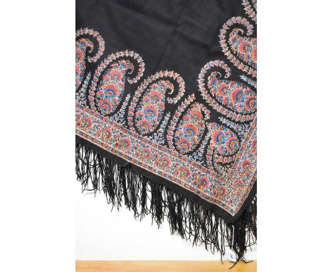 A Victorian silk and wool blend shawl or tablecloth, in black with ornate paisley border, fringing at the edges, some small t