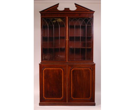 A George III mahogany bookcase cabinet, having an architectural pediment above twin glazed doors enclosing adjustable shelves