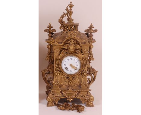 A late 19th century French cast brass mantel clock, the whole profusely cast with grotesque masks, fruit, flowers and C scrol