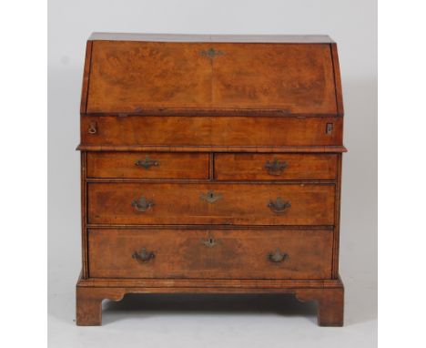 An early 18th century walnut and figured walnut writing bureau (later re-veneered), having cross and feather banded fall encl