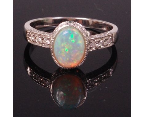 An 18ct white gold opal and diamond dress ring, the cabochon opal in a diamond set surround, the shoulders further set with t