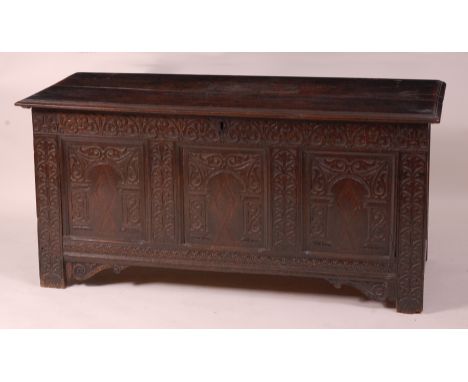 A circa 1700 and later carved joined oak coffer, the hinged lid above a three panel front and on stile end supports (later st