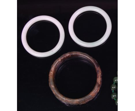 A pair of Chinese polished pale jade bangles, dia.7cm; together with a Chinese carved spinach jade bangle, dia.8cm (3) Condit
