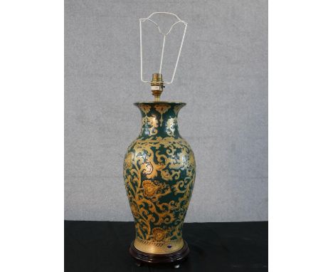 A Chinese porcelain table lamp; with all over gilt painted scroll decoration on green ground; raised on hardwood base with fo