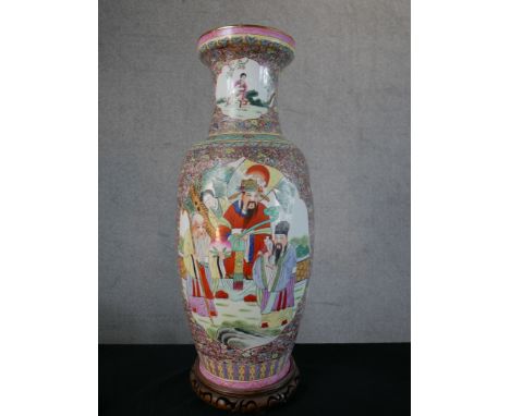 A Chinese porcelain baluster shaped vase decorated with panels of figures in a garden within floral background, raised on pie