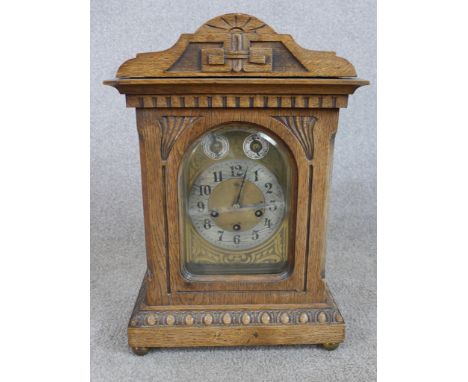 A late 19th/early 20th century carved oak mantle clock, the brass dial with black Arabic numerals, chime and silent dial and 