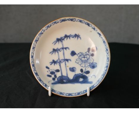 A mid 18th century Chinese café au lait blue and white porcelain saucer dish, decorated with flowers in a rock garden, bearin