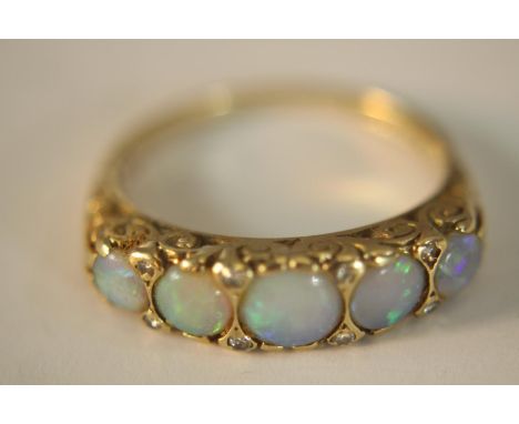 A 9ct carat yellow gold carved half hoop five stone Opal and diamond ring. Set with five round cabochon opals with a combined