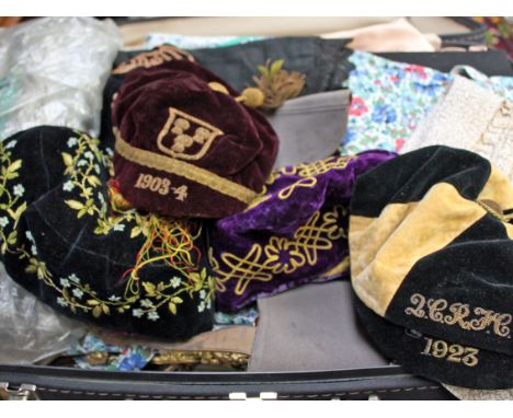 A suit case of various early 20th Century and later textiles including school caps etc. 