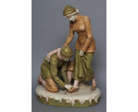 A ROYAL DUX BISQUE PORCELAIN FIGURE GROUP, early 20th century, modelled as two skaters, the young man kneeling and tying the 