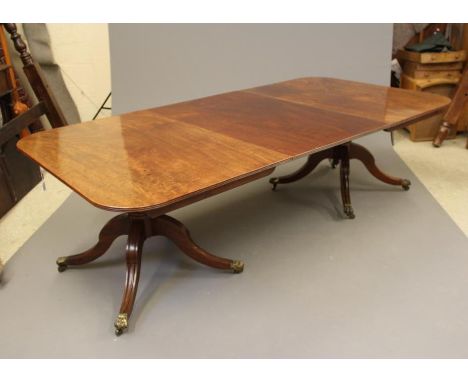 A VICTORIAN MAHOGANY EXTENDING TWIN PEDESTAL DINING TABLE, the reeded edged rounded oblong top with single leaf, on ring and 